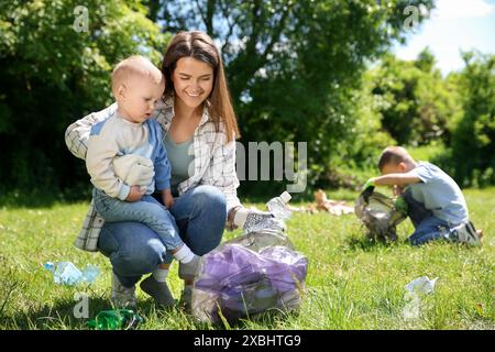 Mutter und ihre Kinder mit Plastiktüten sammeln Müll im Park Stockfoto