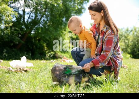 Mutter und Sohn mit Plastiktüte sammeln Müll im Park Stockfoto