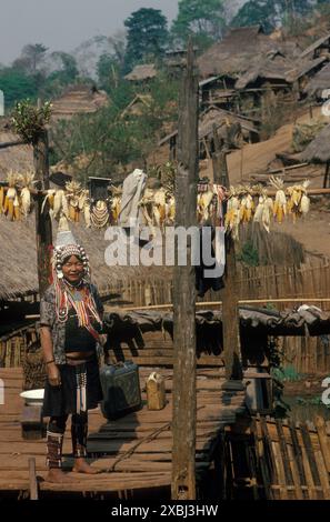 Akha Hill Tribe Indigene in Nordthailand 1995. Ein Akha-Dorf in den Bergen von Nordthailand. Eine Frau in traditioneller alltäglicher einheimischer Tracht steht auf einer erhöhten Plattform ihres Stelzenhauses. Mais trocknet in der Sonne. 1990er Jahre HOMER SYKES Stockfoto