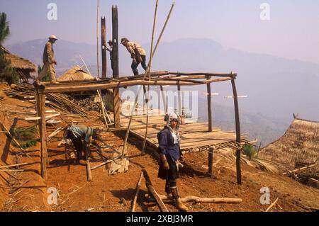 Akha Dorf in den Bergen von Nordthailand 1995. Die Dorfbewohner bauen ein neues Haus mit traditionellen Methoden. Drei Männer arbeiten an der Holzkonstruktion dieses neuen Holzrahmengebäudes. Das auf Stelzen gebaute Rahmenhaus bietet einen wunderbaren Panoramablick über den heimischen Wald. Männer und Frauen, die arbeiten, Frauen tragen traditionelle einheimische Stammesbekleidung Männer in westlicher Kleidung. Akha-Dorf Pala Nordthailand 1990er Jahre HOMER SYKES Stockfoto