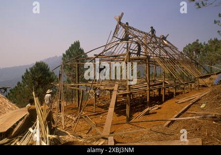 Akha Dorf in den Bergen von Nordthailand 1995. Die Dorfbewohner bauen ein neues Haus mit traditionellen Methoden. Männer arbeiten an der Holzkonstruktion dieses neuen Holzrahmengebäudes. Das auf Stelzen gebaute Rahmenhaus bietet einen wunderbaren Panoramablick über den heimischen Wald. Akha-Dorf Pala Nordthailand 1990er Jahre HOMER SYKES Stockfoto