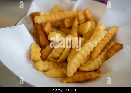 Nahaufnahme von Pommes Frites, serviert auf Papier in einer Schüssel Stockfoto