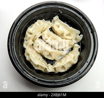 Nahaufnahme chinesischer gedämpfter Teigtaschen in einem Take-away-Behälter (asiatisches Schweinefleisch gefüllt Dim Sum Vorspeise), schwarzer Kunststoff-To Go-Teller-Box (Dampf Do Stockfoto