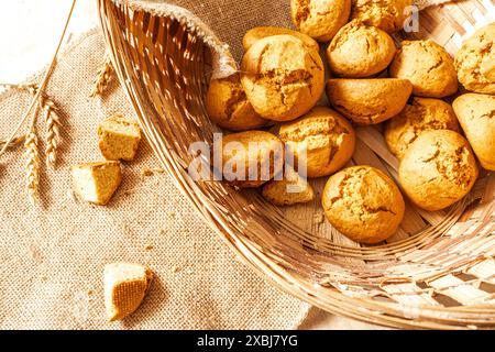 Kleine Brötchen in einem Korb und Weizenohren auf Leinwand. Frühstücksgebäck zum Frühstück. Ausgewählter Fokus. Hochwertige Fotos Stockfoto