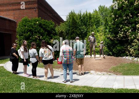 Mt. Airy, NC, USA-1. Juni 2024: Eine Gruppe von Menschen bewundern die Statue von Andy und Opie auf dem Gelände des Andy Griffith Spielhauses und Museums. Stockfoto