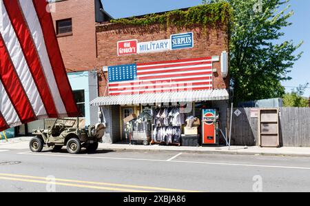 Clyde, NC, USA-4. Mai 2023: Old Grouch's Military Surplus Store und Nahaufnahme der amerikanischen Flagge in der linken Bildecke. Stockfoto