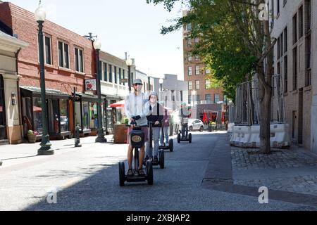 Asheville, NC, USA-4. Mai 2023: Eine Reihe von Motorrollern im Segway-Stil, die durch die Stadt fahren. Stockfoto