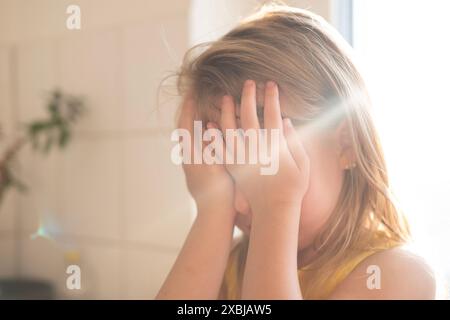 Kleines Kind 5 Jahre alt, blondes Mädchen weint, Gesicht bedeckt, frühzeitige Diagnose und Intervention, Unterstützung für Menschen mit Autismus, Schutzhaltung, Kompl Stockfoto