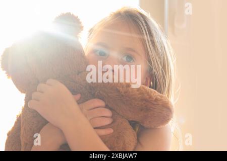 Kleines Kind 5 Jahre alt, blondes Mädchen mit Spielzeug-Teddybär, Früherkennung und Intervention, Unterstützung für Menschen mit Autismus, Schutzhaltung, Selbstzufriedenheit Stockfoto