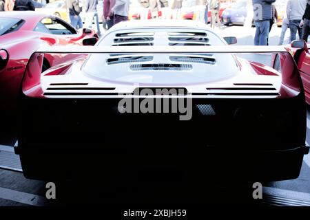 Ein Foto von hinten eines Ferrari F40 mit Details im hinteren Teil, die sich im Schatten einer Parkgarage verstecken und die Morgensonne das Dach hervorheben. Stockfoto