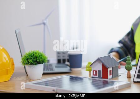 Ingenieure prüfen Pläne von Architekten zur Vorbereitung der Installation von Solarpaneelen und Windturbinen im Gebäude, um Strom effizient zu erzeugen Stockfoto