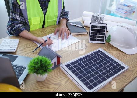 Ingenieure prüfen Pläne von Architekten zur Vorbereitung der Installation von Solarpaneelen und Windturbinen im Gebäude, um Strom effizient zu erzeugen Stockfoto