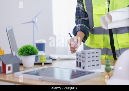 Ingenieure prüfen Pläne von Architekten zur Vorbereitung der Installation von Solarpaneelen und Windturbinen im Gebäude, um Strom effizient zu erzeugen Stockfoto