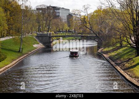 Eine Fußgängerbrücke über den Fluss und ein kleines Boot im Fluss unterhalb der Brücke Stockfoto