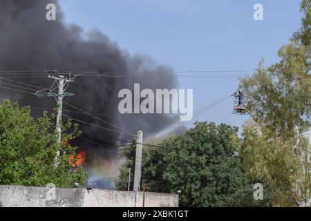 Athen, Griechenland. 12. Juni 2024. Flammen und schwarzer Rauch steigen in den Himmel, während Feuerwehrleute in einer Kochgeschirrfabrik im nördlichen Athener Vorort Kifissia mit einem Feuer kämpfen, das durch mehrere Explosionen verursacht wurde. Die Behörden warnten die Bewohner, wegen einer möglichen toxischen Wolke drinnen zu bleiben. Quelle: Dimitris Aspiotis/Alamy Live News Stockfoto