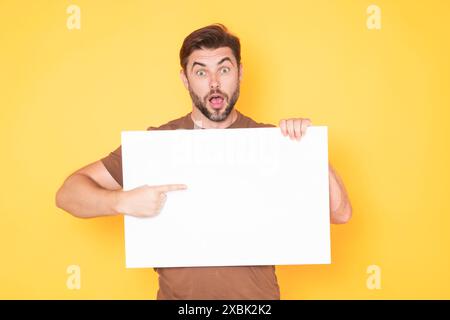 Mann mittleren Alters mit leerem Plakat. Darstellung des Kopierbereichs für Ihren Text oder Ihr Design. Ein Mann, der eine leere Werbetafel im Studiohintergrund zeigt Stockfoto