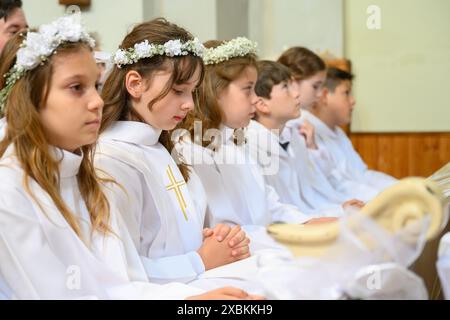 Kinder in Bänken bei ihrer ersten Kommunionmesse. Stockfoto