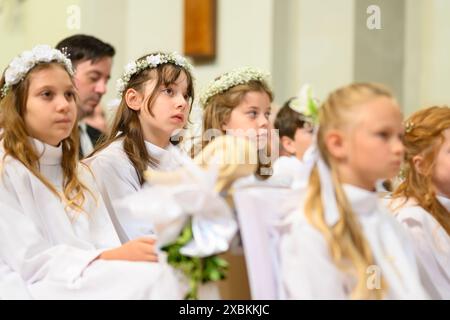 Kinder in Bänken bei ihrer ersten Kommunionmesse. Stockfoto