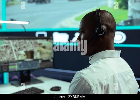 afroamerikaner überwacht die Verkehrsaktivität per CCTV-System, mit Überwachungsaufnahmen und Radar in der Stadt. Mitarbeiter des Kontrollzentrums verfolgen Autos durch Überwachungskameras. Stockfoto