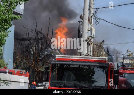 Athen, Griechenland. 12. Juni 2024. Flammen und schwarzer Rauch steigen in den Himmel, während Feuerwehrleute in einer Kochgeschirrfabrik im nördlichen Athener Vorort Kifissia mit einem Feuer kämpfen, das durch mehrere Explosionen verursacht wurde. Die Behörden warnten die Bewohner, wegen einer möglichen toxischen Wolke drinnen zu bleiben. Quelle: Dimitris Aspiotis/Alamy Live News Stockfoto