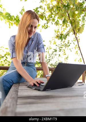 Frau lernt und benutzt Laptop in einem Restaurant im Freien Stockfoto