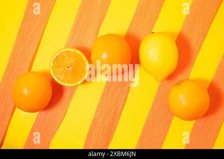 Orangen und Zitronen auf gelb-orangefarbenem Hintergrund. Kreatives Sommerkonzept. Stockfoto