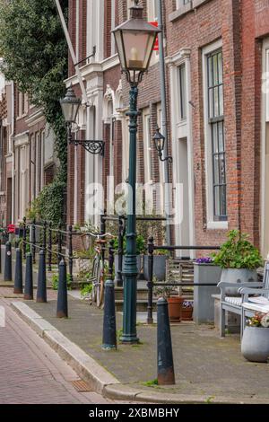 Altstadtstraße mit klassischen Laternen und Fahrrädern vor gepflegten Backsteingebäuden, Dordrecht, holland, niederlande Stockfoto
