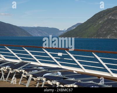 Auf dem Deck eines Kreuzfahrtschiffs mit Blick auf einen ruhigen, blauen Fjord, Flam, Norwegen stehen mehrere Sonnenliegen Stockfoto