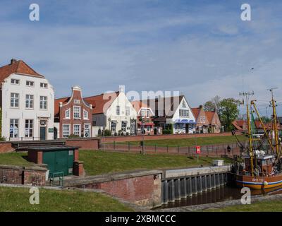 Blick auf eine Reihe von farbenfrohen historischen Häusern entlang eines Hafens mit Booten und sonnigem Wetter, greetsiel, ostfriesland, deutschland Stockfoto