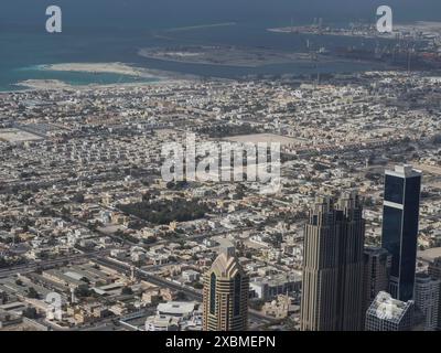 Aus der Vogelperspektive auf eine urbane Landschaft mit Hochhäusern in der Nähe der Küste und verschiedenen Hafenanlagen, Dubai, Arabische Emirate Stockfoto