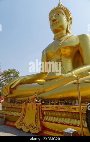 Gigantische goldene Buddha-Statue in Lotusposition mit Ornamenten auf dem Sockel, davor religiöse Objekte, Pattaya, Thailand Stockfoto