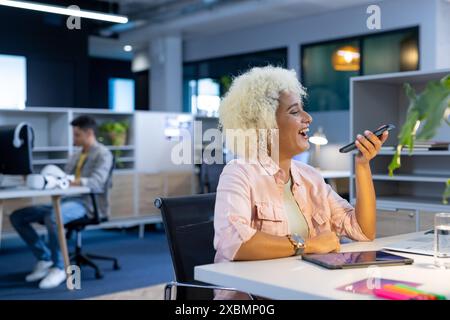 Birassische Frau lächelt beim Telefonieren mit Smartphone in modernen Büros, Unternehmen, Kopierräumen Stockfoto