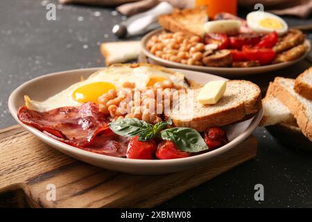 Teller mit leckerem englischem Frühstück auf schwarzem Hintergrund Stockfoto