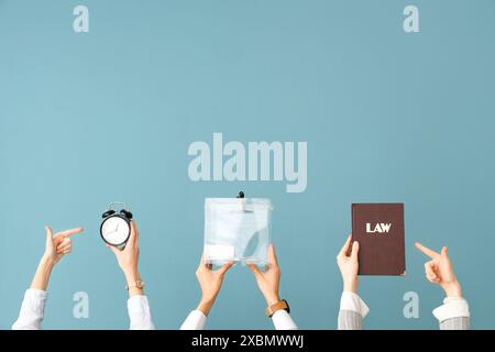 Hände, die Stimmzettel halten, Gesetzbuch und Wecker auf blauem Hintergrund. Wahlkonzept Stockfoto
