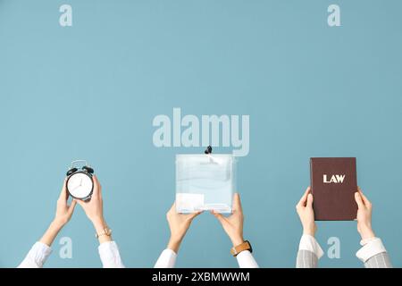 Hände, die Stimmzettel halten, Gesetzbuch und Wecker auf blauem Hintergrund. Wahlkonzept Stockfoto