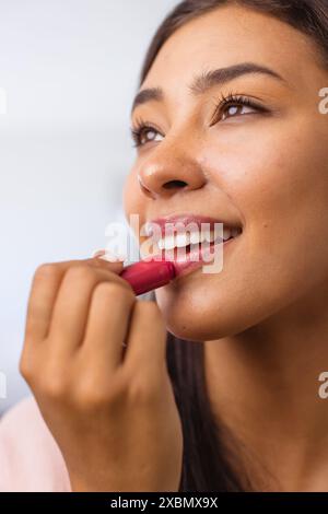 Glückliche Frau, die Lippenstift aufträgt und sanft lächelt Stockfoto