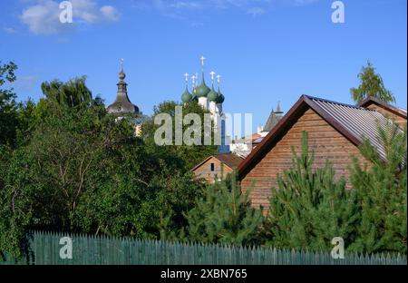 Blick auf Gärten und Holzhäuser vor dem Hintergrund der Kuppeln der mittelalterlichen Kirchen in Rostow dem Großen Stockfoto