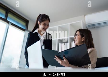 Professionelles Geschäftstreffen in modernem Büroumfeld mit zwei weiblichen Kollegen, die Dokumente diskutieren und am Projekt zusammenarbeiten Stockfoto
