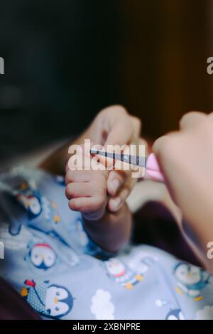 Eine Mutter schneidet ihrer Tochter den Nagel an der Fingerhand Stockfoto