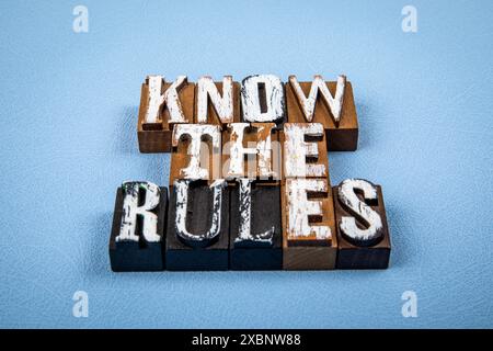 DIE REGELN KENNEN. Hölzerne Buchstabenblöcke auf blau strukturiertem Hintergrund. Stockfoto