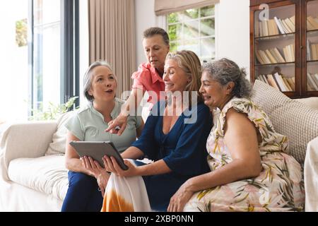 Verschiedene Seniorinnen, die ihr Tablet zu Hause auf dem Sofa nutzen Stockfoto