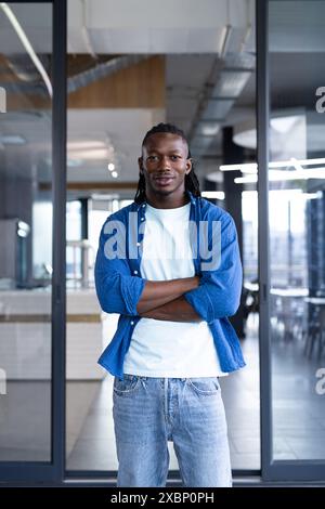 Ein afroamerikanischer Mann steht selbstbewusst mit gekreuzten Armen im Geschäft Stockfoto