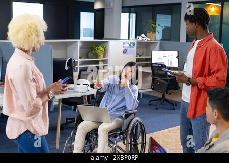 Verschiedene Geschäftskollegen arbeiten zusammen; Frau im Rollstuhl, die an einem Laptop arbeitet, Teamarbeit Stockfoto