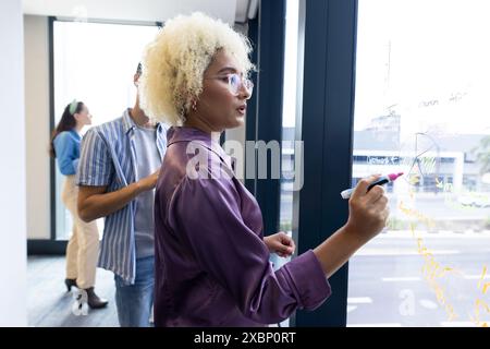 Birassische Frau schreibt am Fenster, Geschäft, Brainstorming Stockfoto