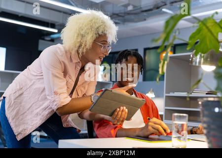 Biracial Woman arbeitet mit einem afroamerikanischen Mann mit einem Tablet zusammen Stockfoto