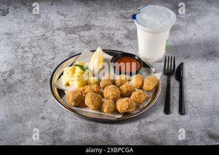 Gebratene Muscheln auf einem Metallteller mit Kartoffelsalat auf der Seite. Türkischer Name: Midye Tava Stockfoto