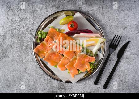 Räucherlachs mit Gemüse darunter auf einem Steintisch Stockfoto