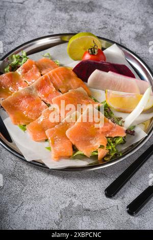 Räucherlachs mit Gemüse darunter auf einem Steintisch Stockfoto