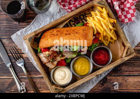 Steak-Sandwich mit Saucen und Pommes frites auf Holztisch Stockfoto