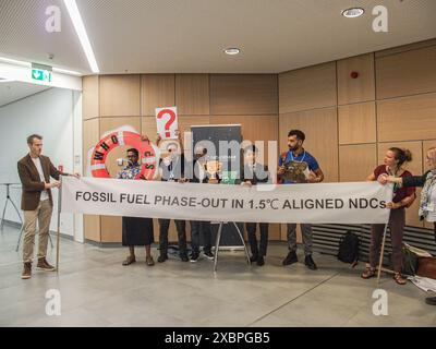 Bonn, Deutschland, Deutschland. Juni 2024. Ein Greenpeace-Demonstrant posiert für die Kamera nach einem kleinen freundlichen Protest mit einem Schild Fossil Fuel Phase-out während des UNFCCC, SB 60, das im Weltkonferenzzentrum in Bonn stattfand. Dies ist die Vorbereitung der COP29-Veranstaltung, die im November dieses Jahres in Baku, Aserbaidschan, stattfinden wird. (Kreditbild: © Bianca Otero/ZUMA Press Wire) NUR REDAKTIONELLE VERWENDUNG! Nicht für kommerzielle ZWECKE! Stockfoto